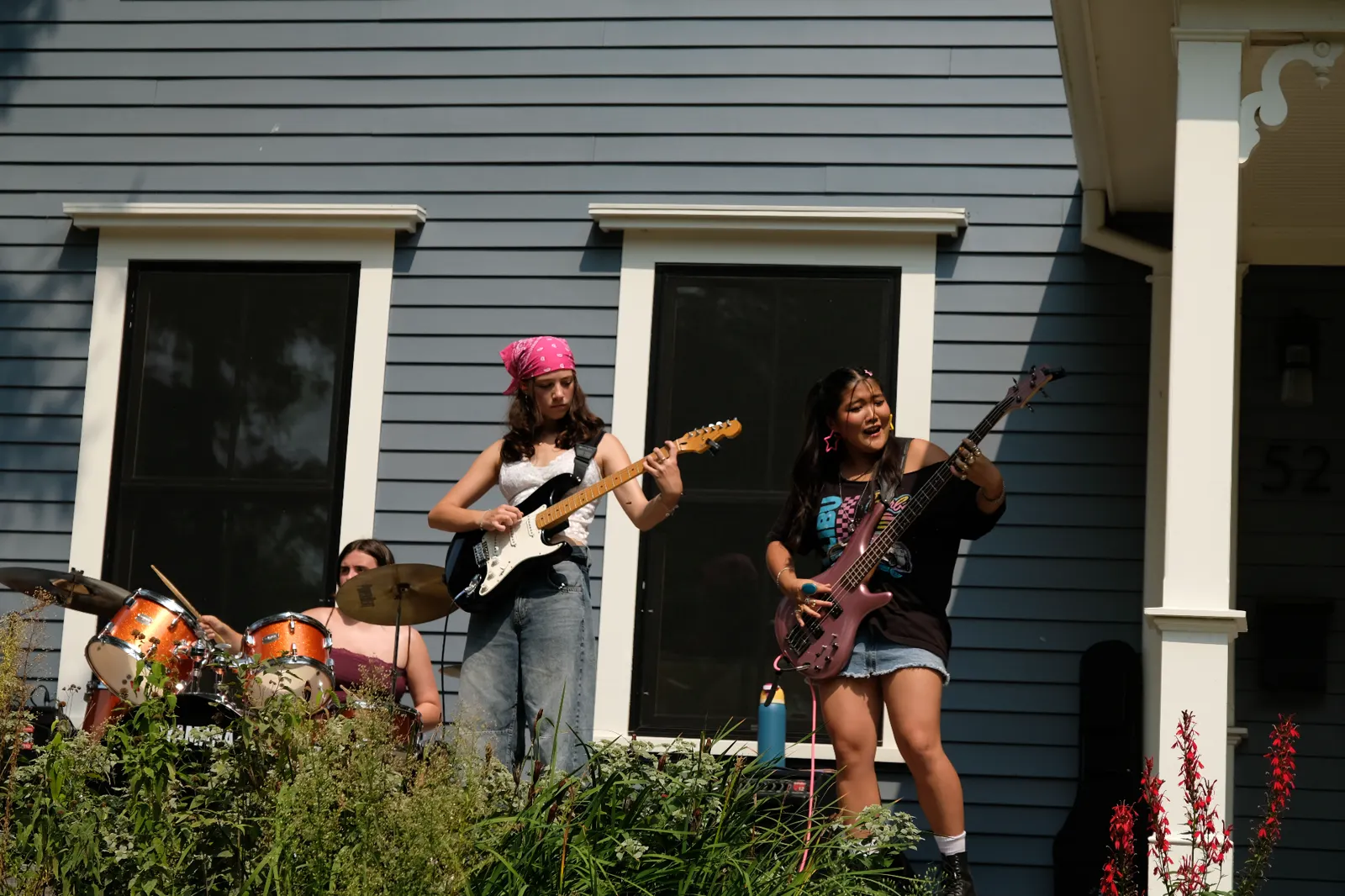 Guitar and bass duo performing on porch with drums