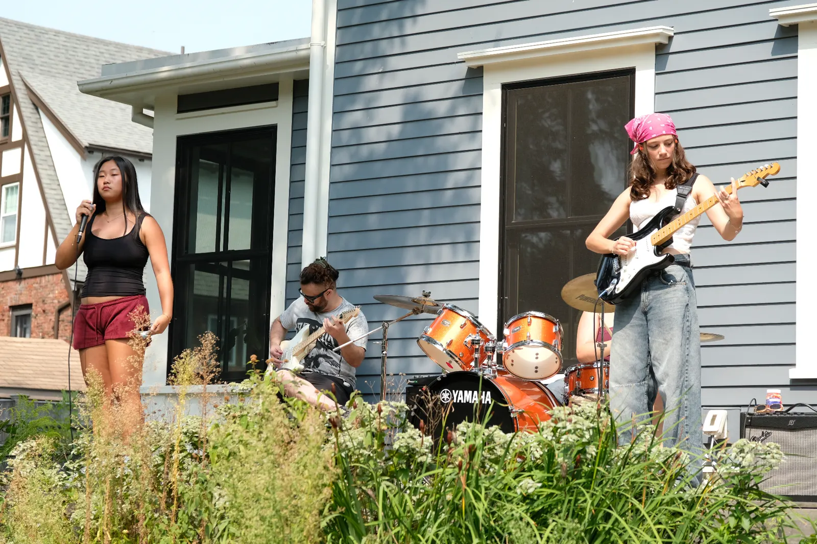 Vocalist with drummer and guitarist performing outdoors