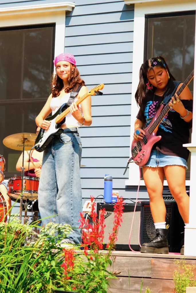 Students playing guitar and bass at outdoor performance